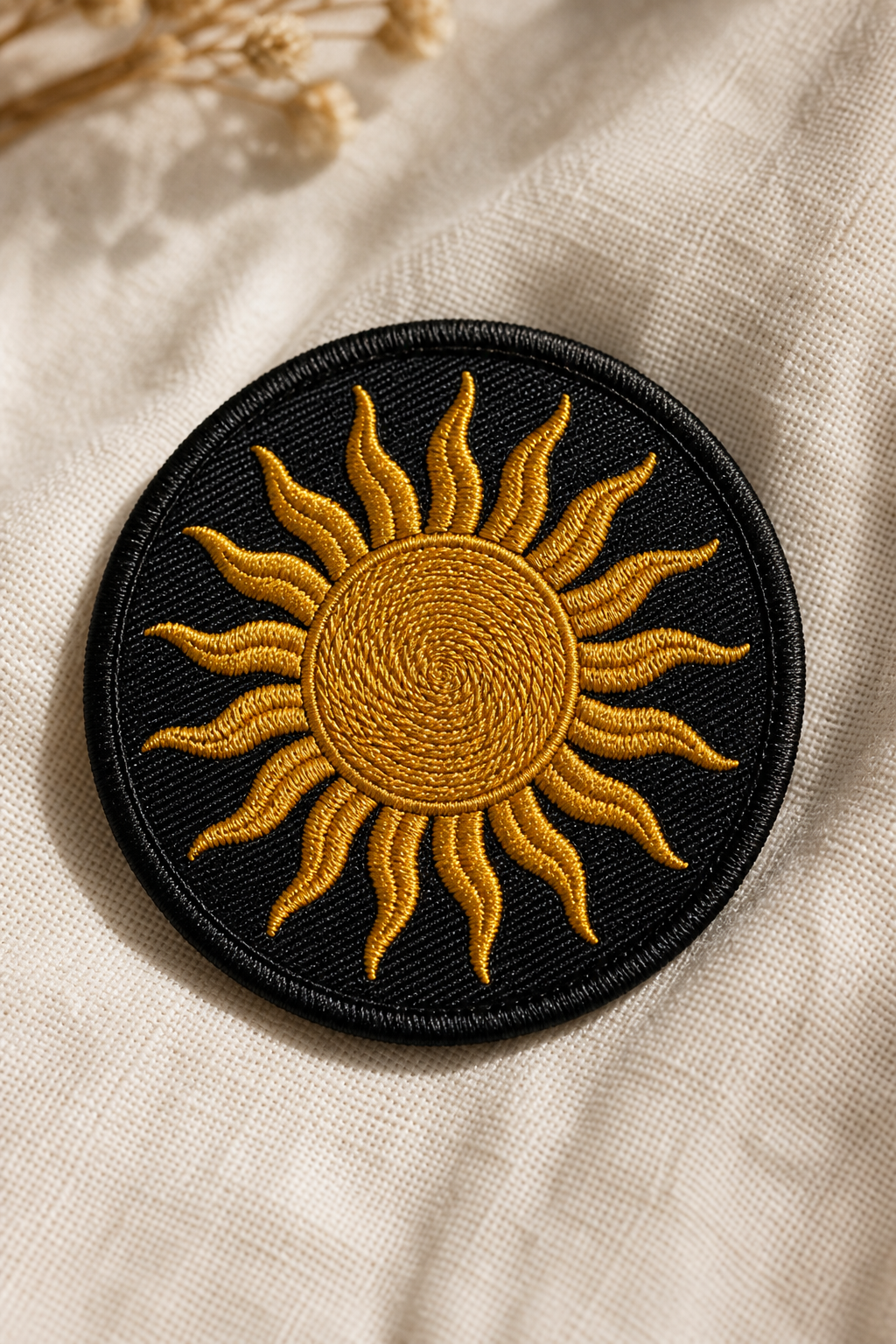 Round embroidered patch of the Zagros Sun in gold thread on black twill